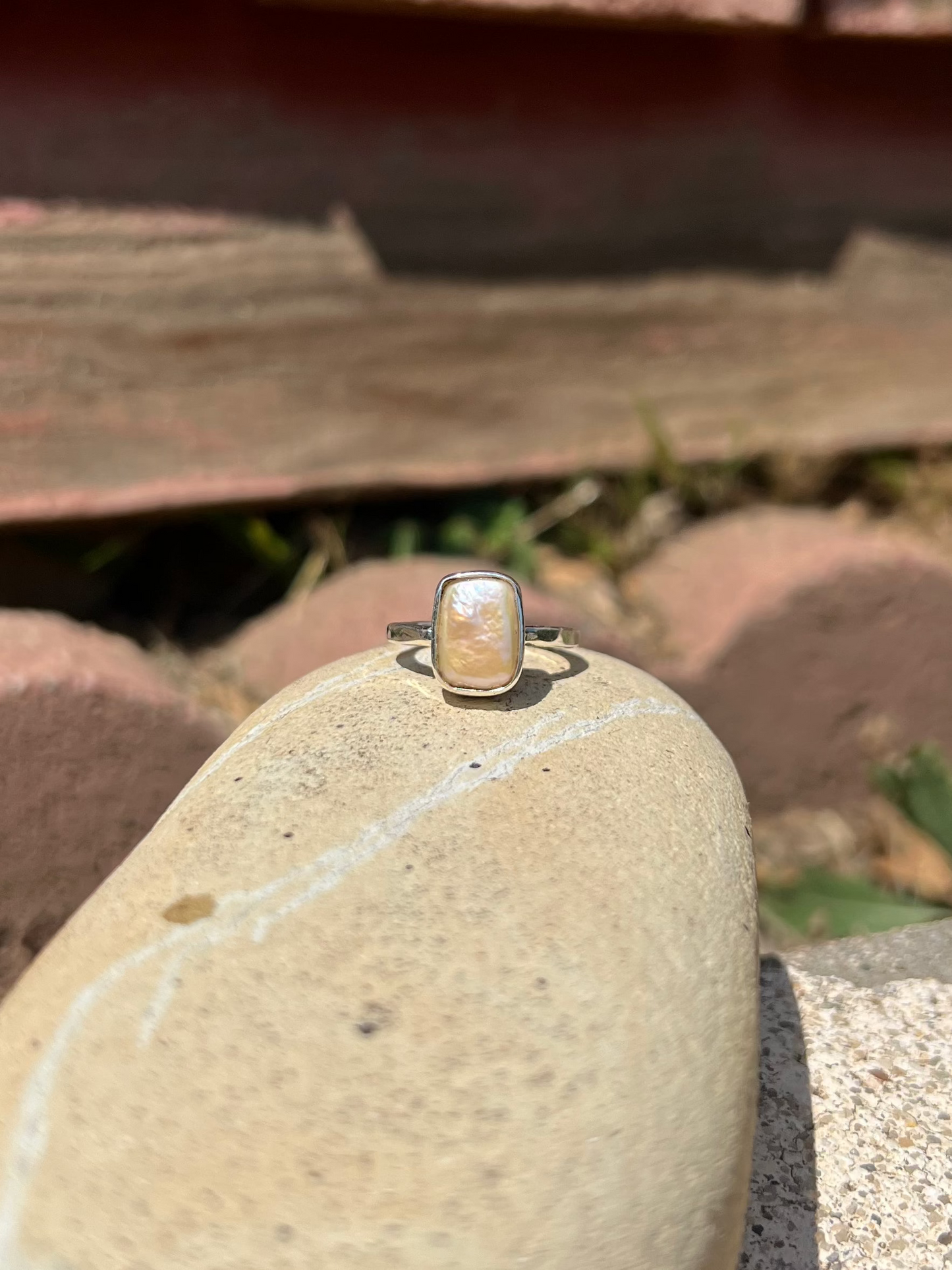 Ring on a rock with wooden planks and grass in the background