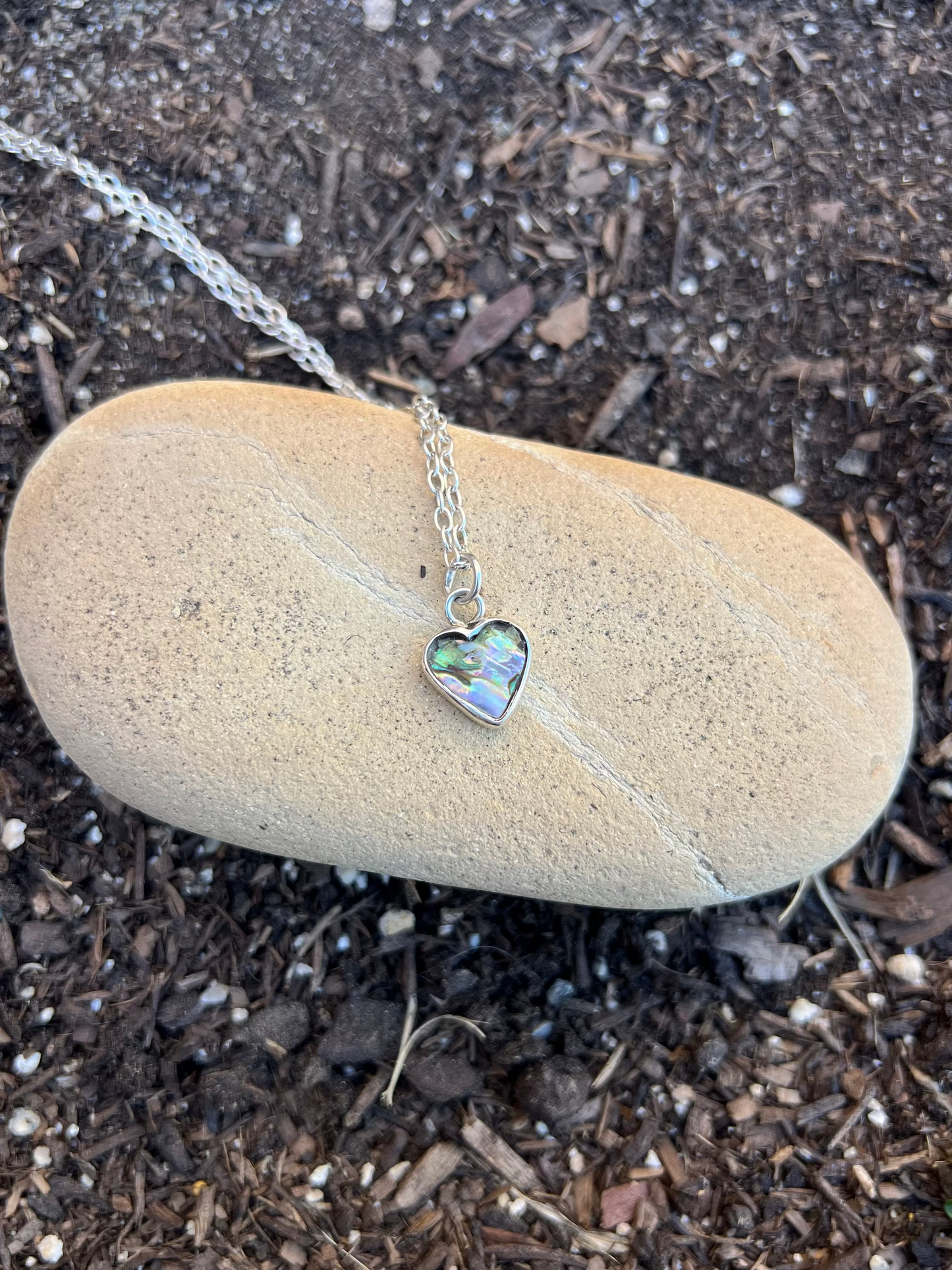 Heart-shaped pendant necklace on a stone with soil background