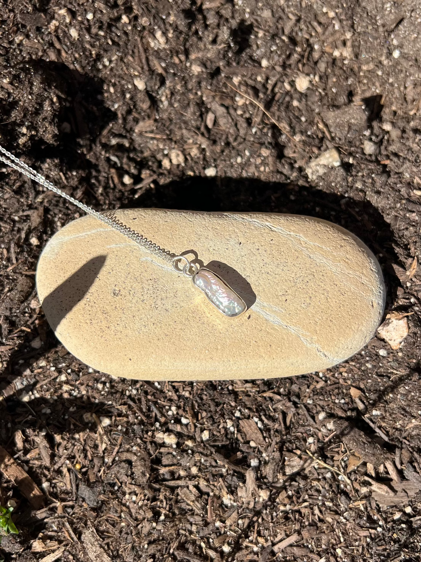 pearl necklace sitting on a rock in a garden