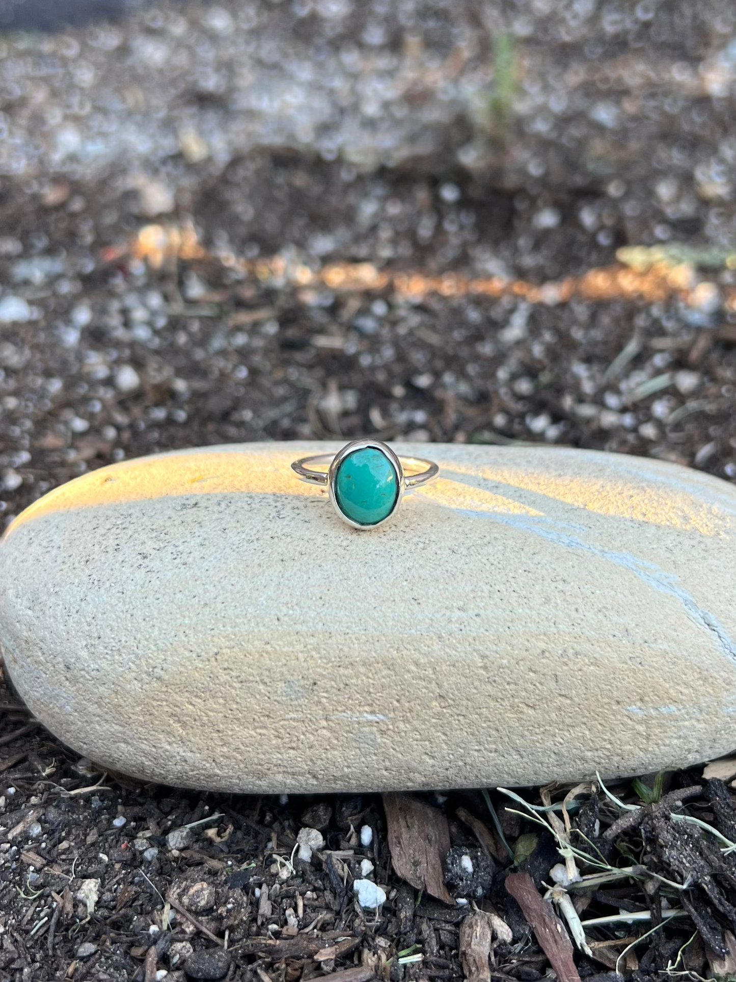 Ring with a turquoise stone on a stone in a garden setting