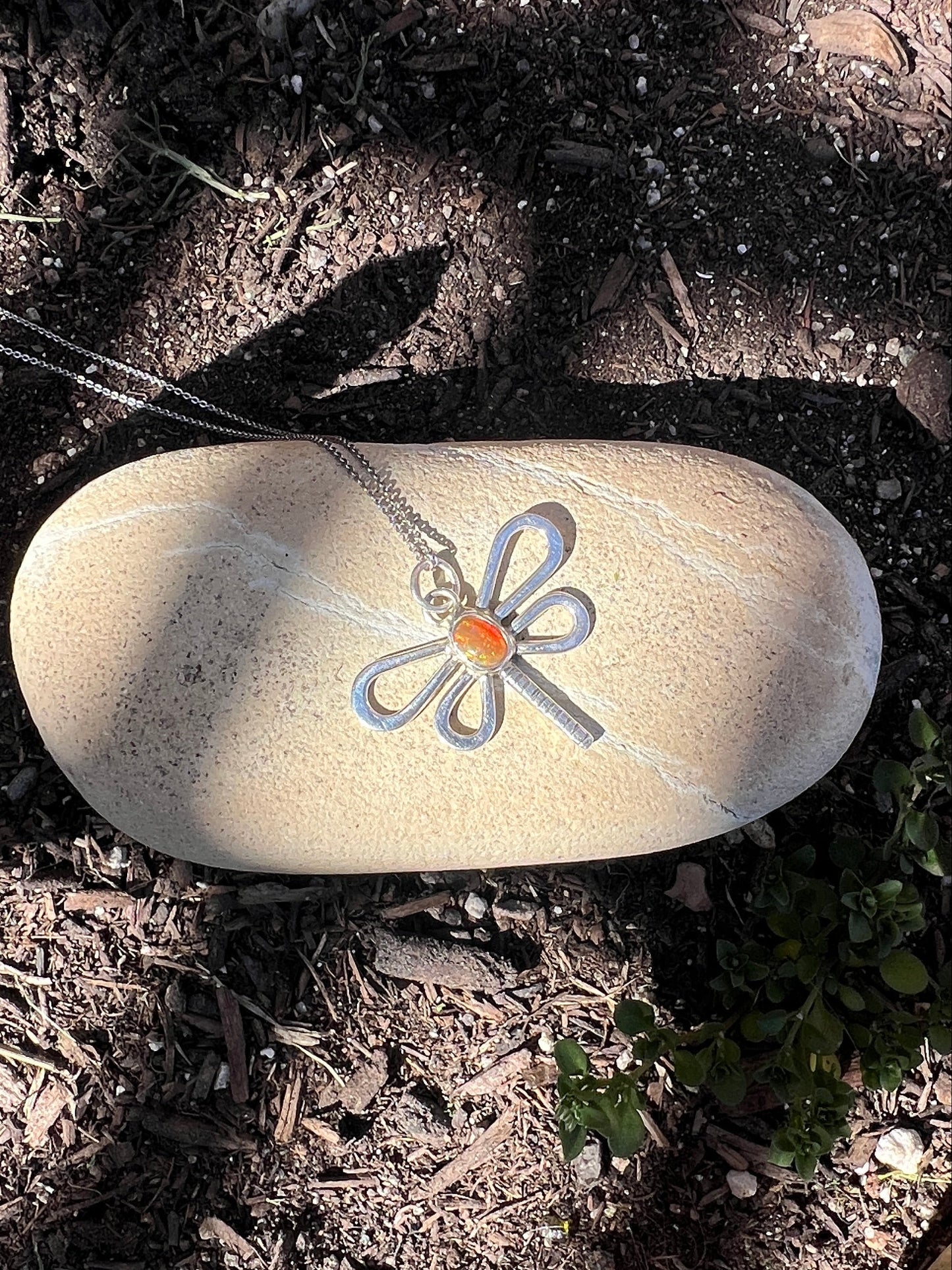 dragonfly shaped necklace design on a natural ground background