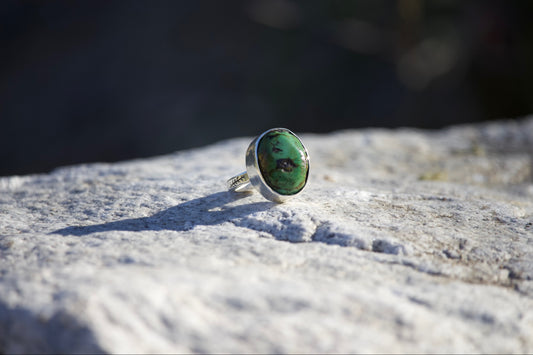Ring with a green stone on a textured surface