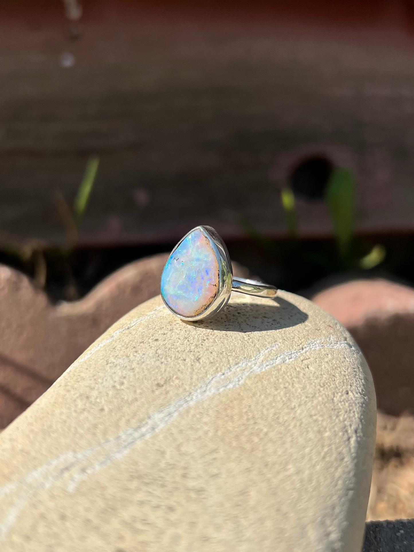 Opal ring on a rock with a wooden background
