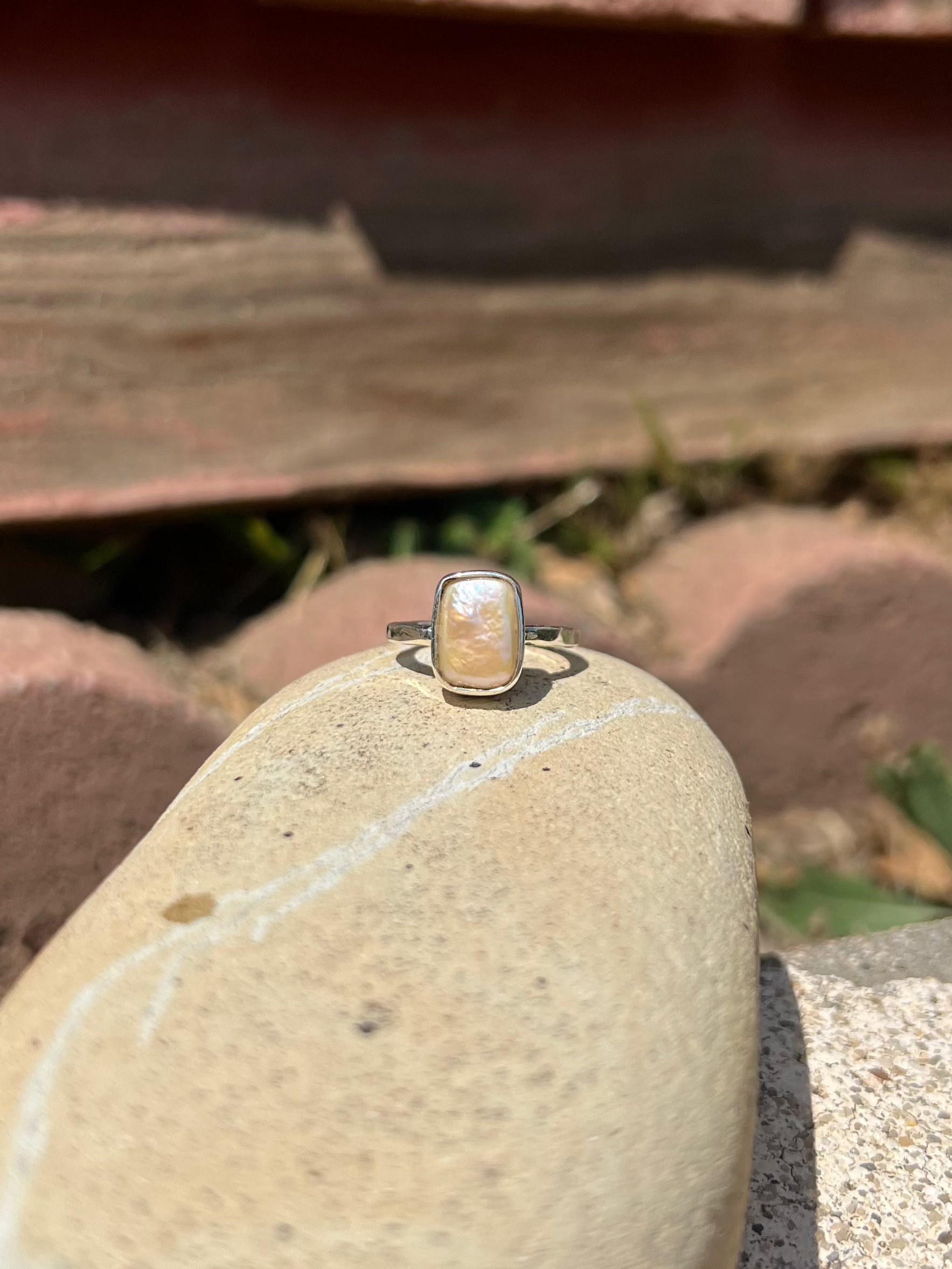 Ring on a rock with wooden planks and grass in the background