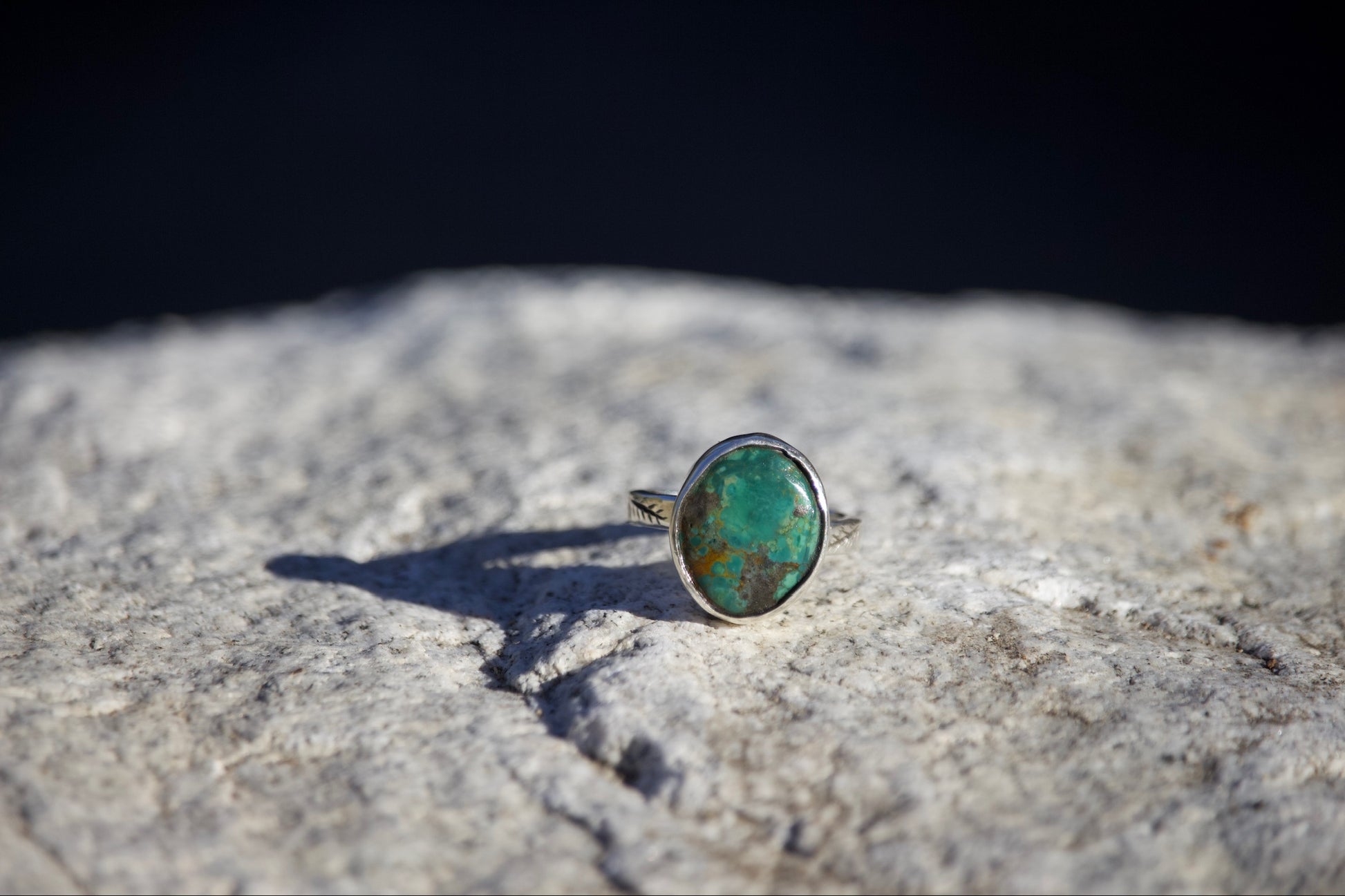 Ring with a green stone on a textured surface