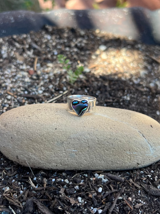 Silver ring with a blue heart design on a stone outdoors