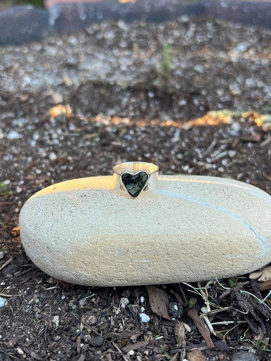 Round stone with a heart-shaped depression on a bed of soil
