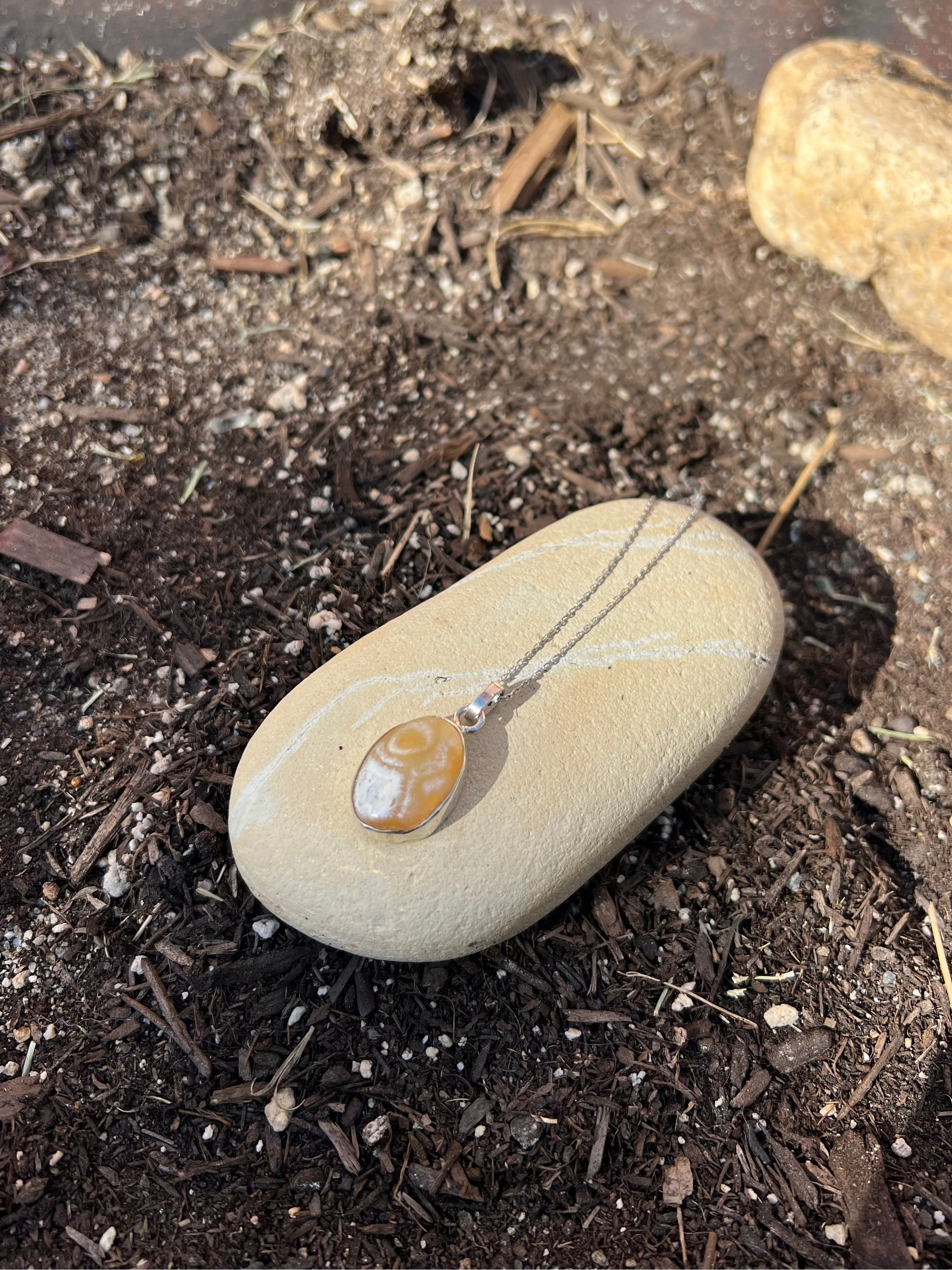 Necklace with a pendant on a stone amidst soil and small rocks