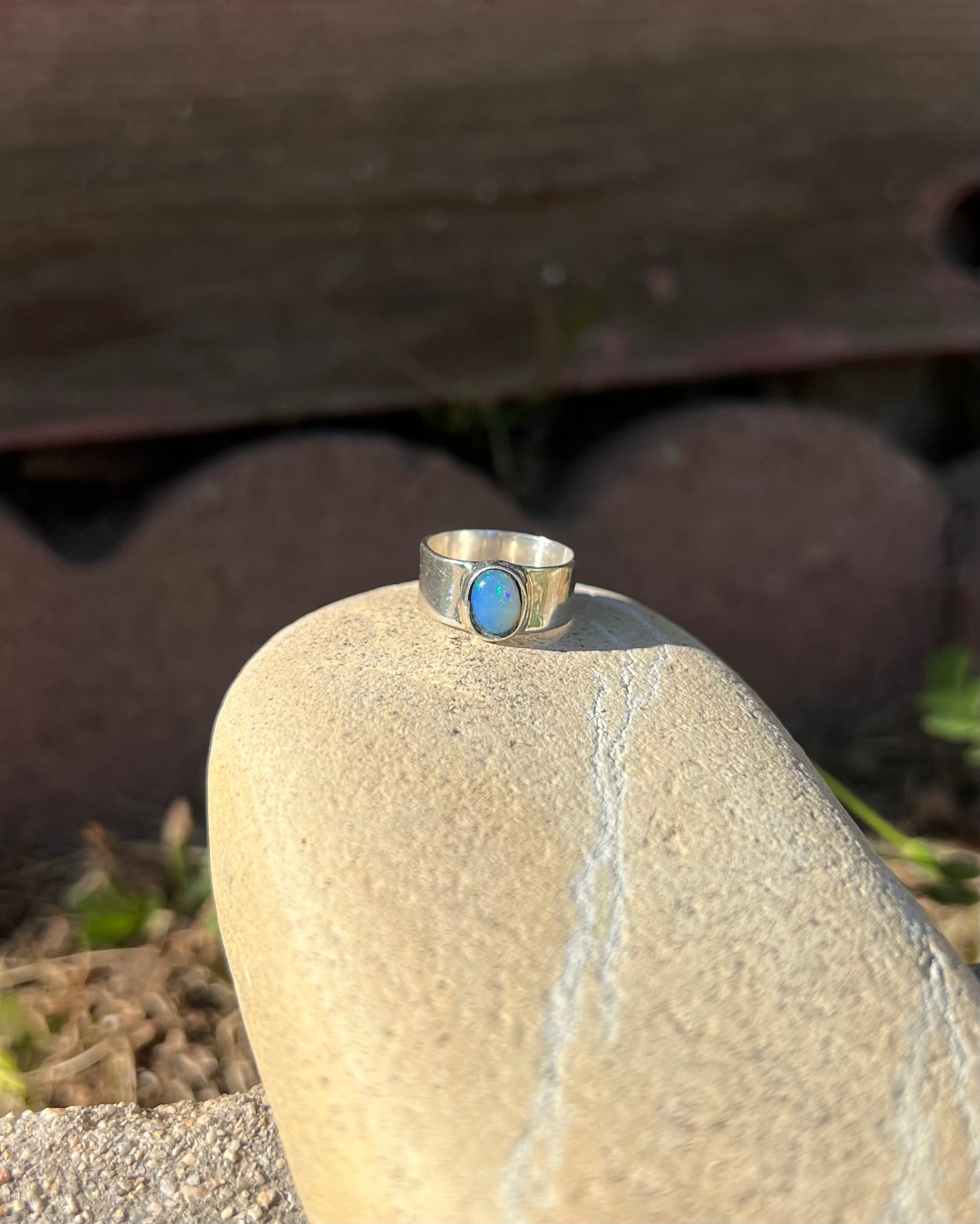 Silver ring with a blue stone on a rock