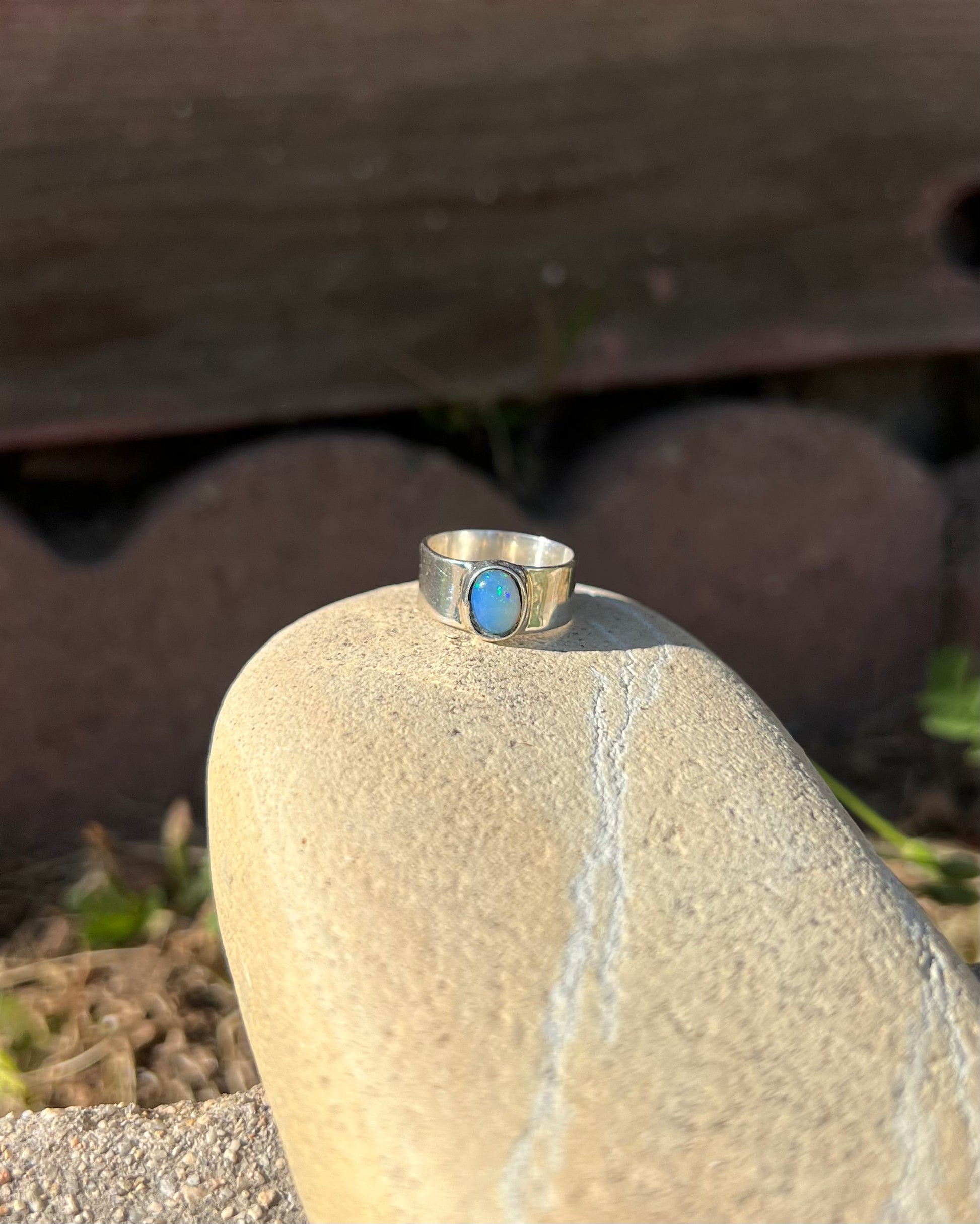 Silver ring with a blue stone on a rock