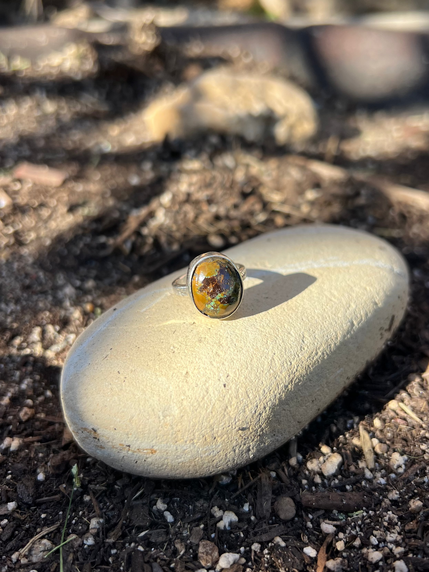 Ring with a colorful stone on a rock in a natural setting