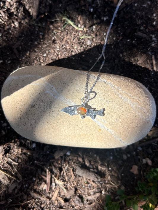 Silver necklace with a pendant on a rock in a natural setting