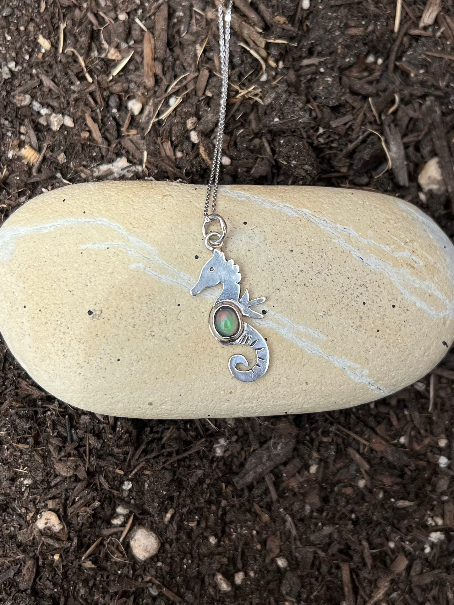 dainty sterling silver seahorse necklace on a rock 