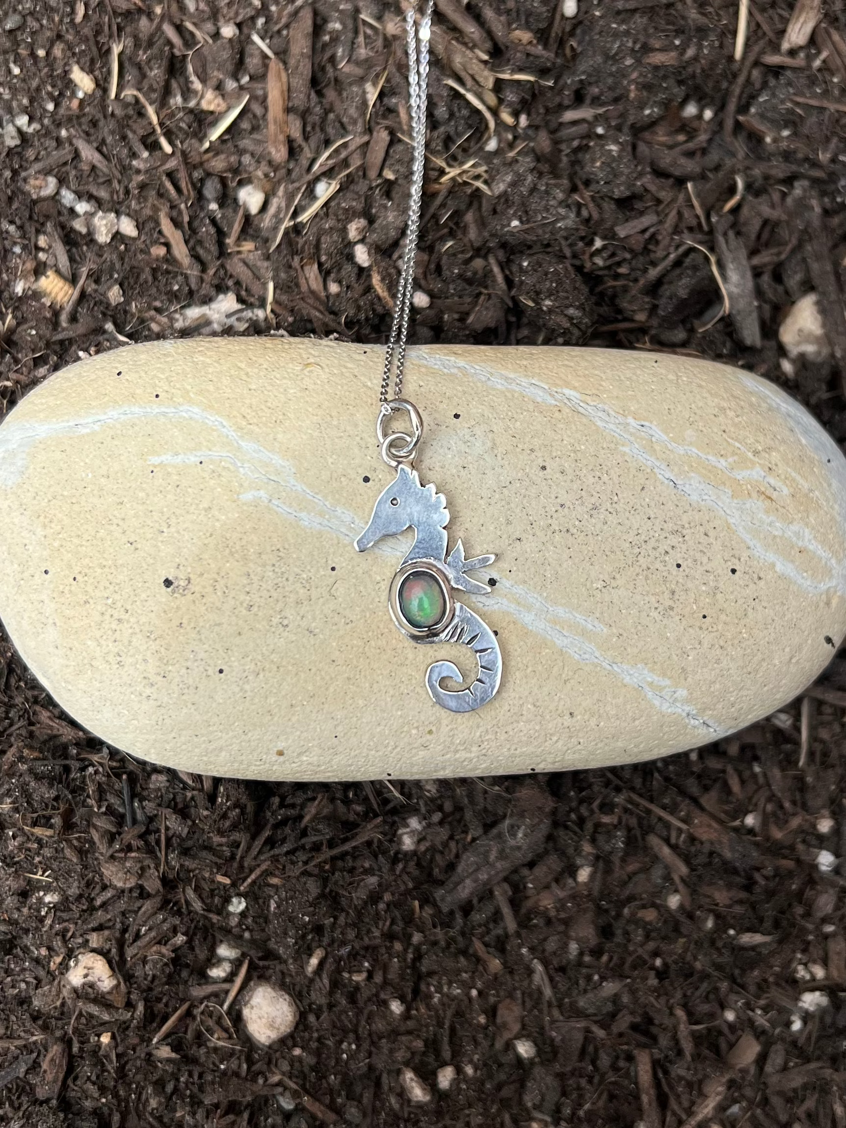 dainty sterling silver seahorse necklace on a rock 
