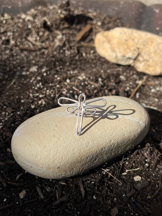 Silver dragonfly pendant on a stone in a natural setting