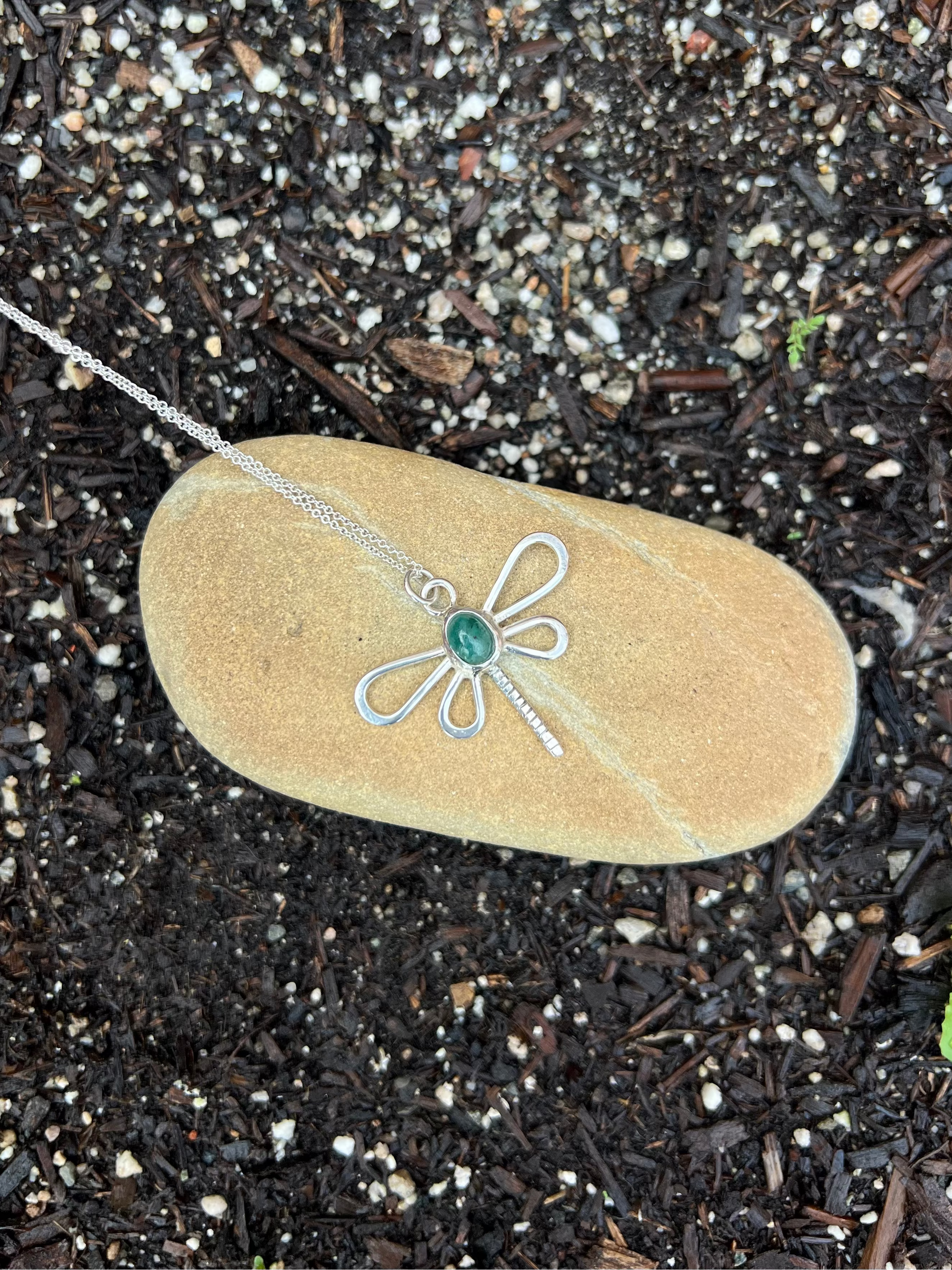dragonfly shaped necklace on a stone 