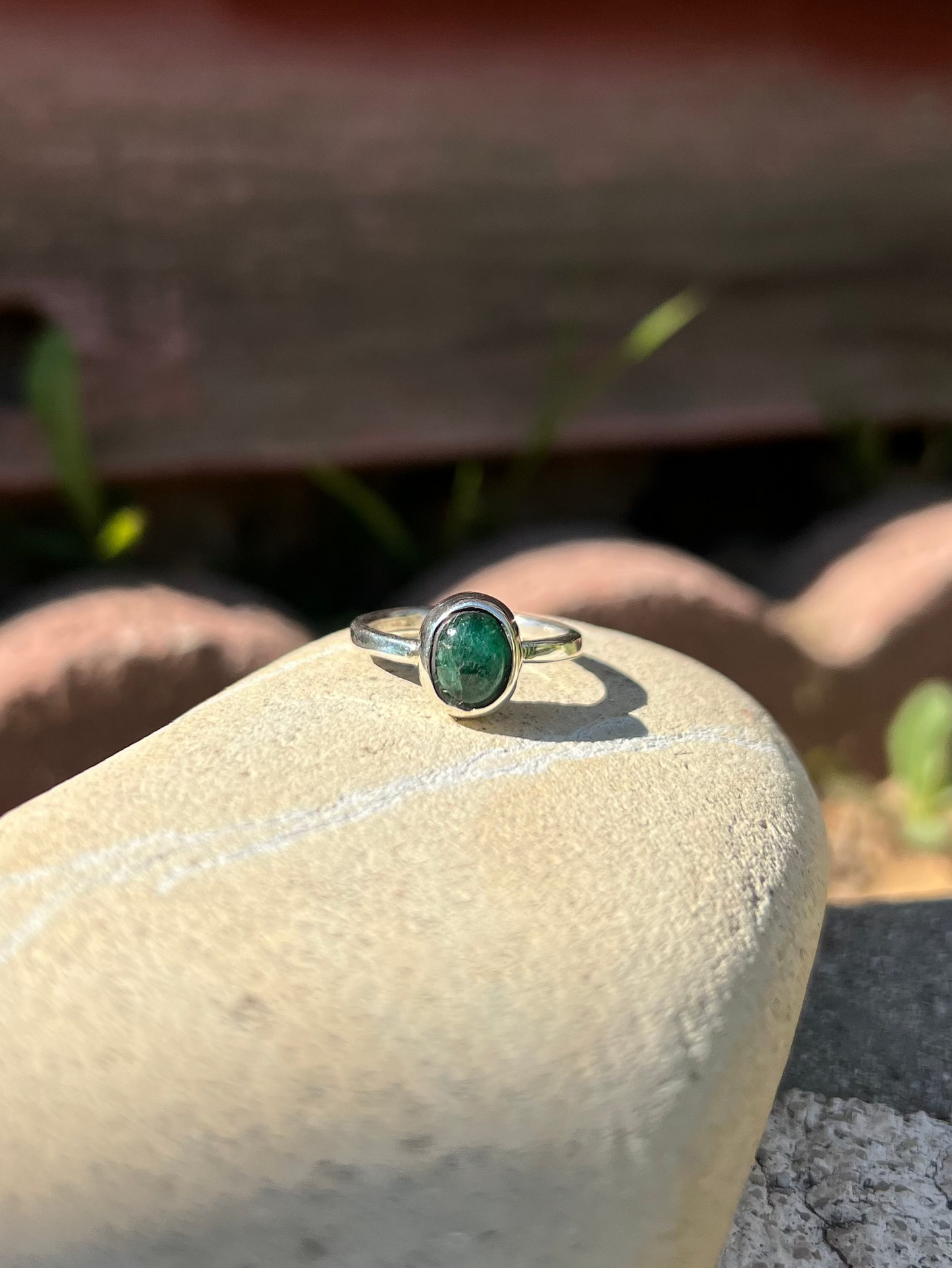 Ring with a green stone on a rock with a brick background
