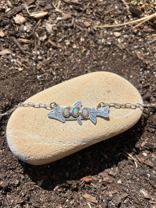 fish. necklace sitting on a rock 