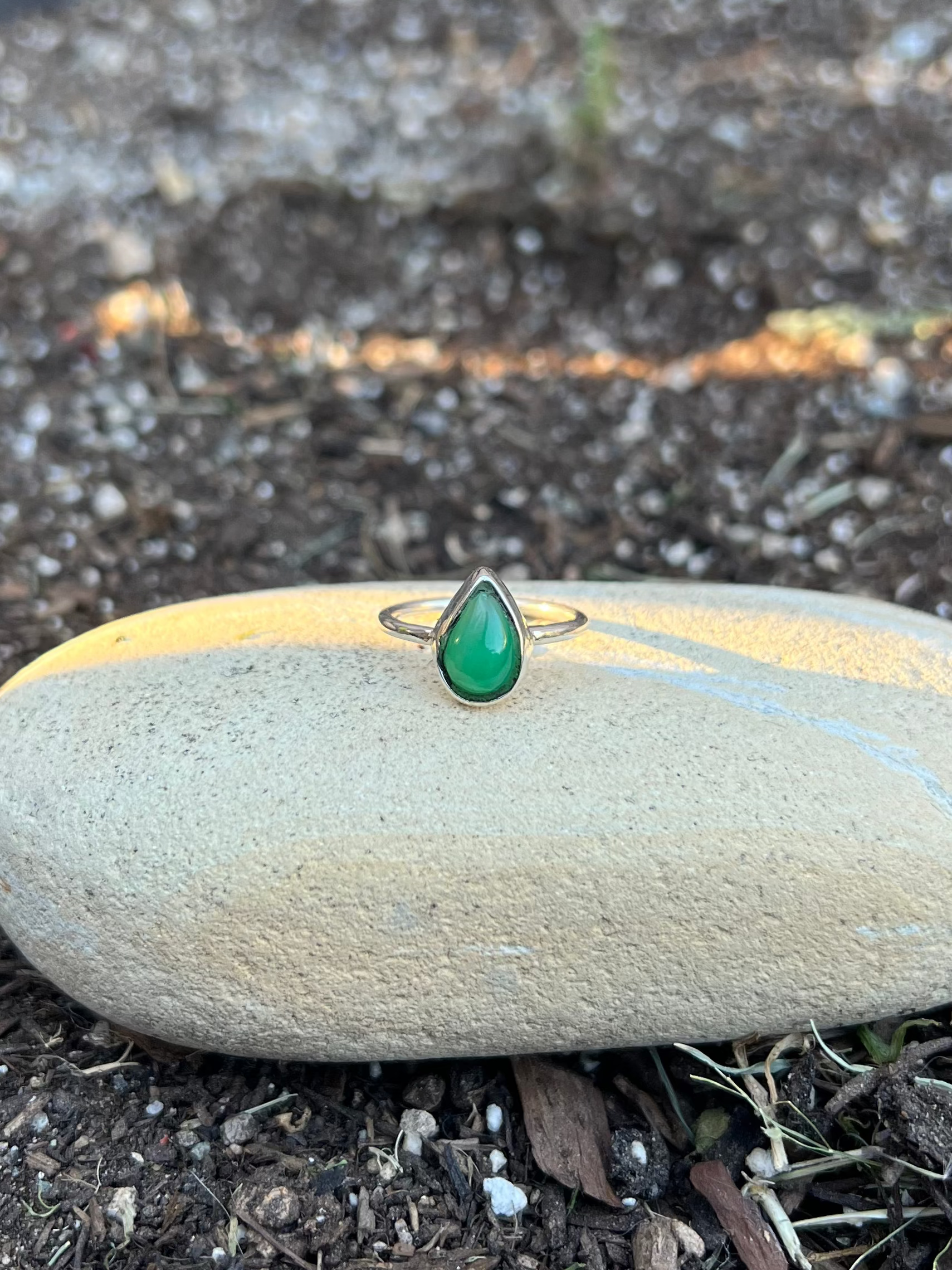 green stone tear drop sterling silver ring on a rock