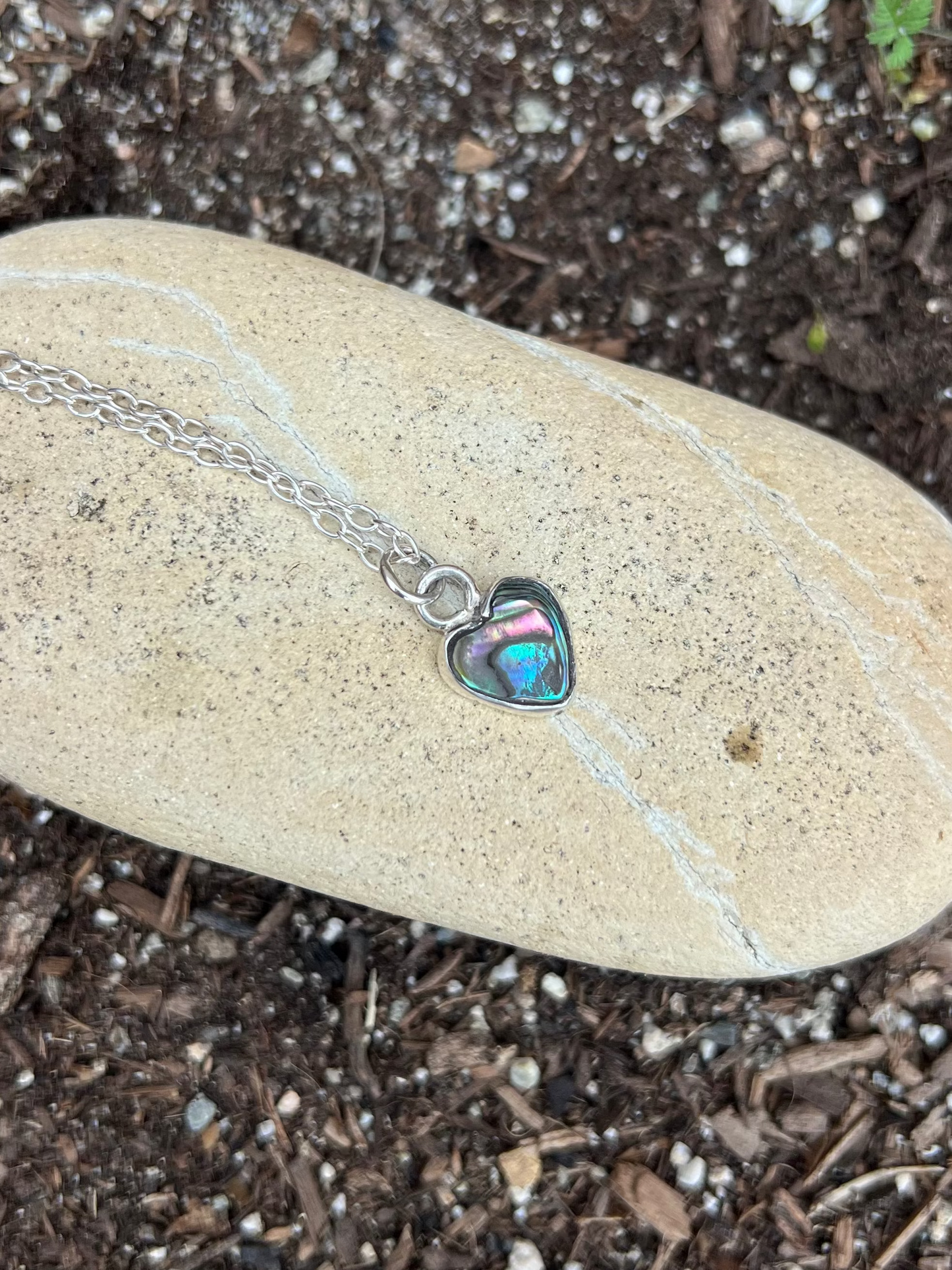 Necklace with a heart-shaped pendant on a rock in a natural setting