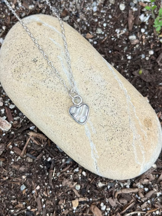 Necklace with a heart pendant on a stone in soil
