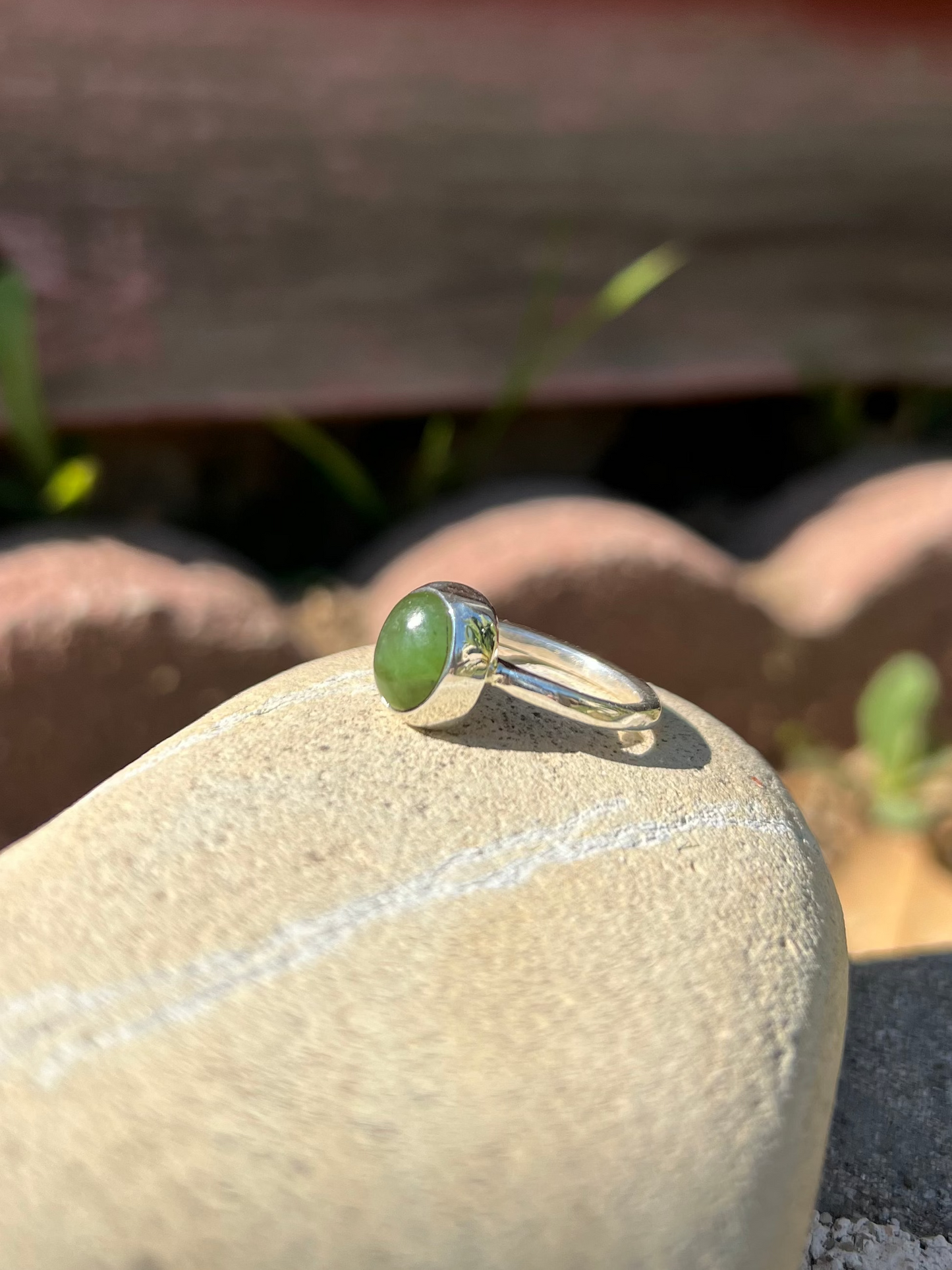 Ring with a green stone on a rock with a concrete block background
