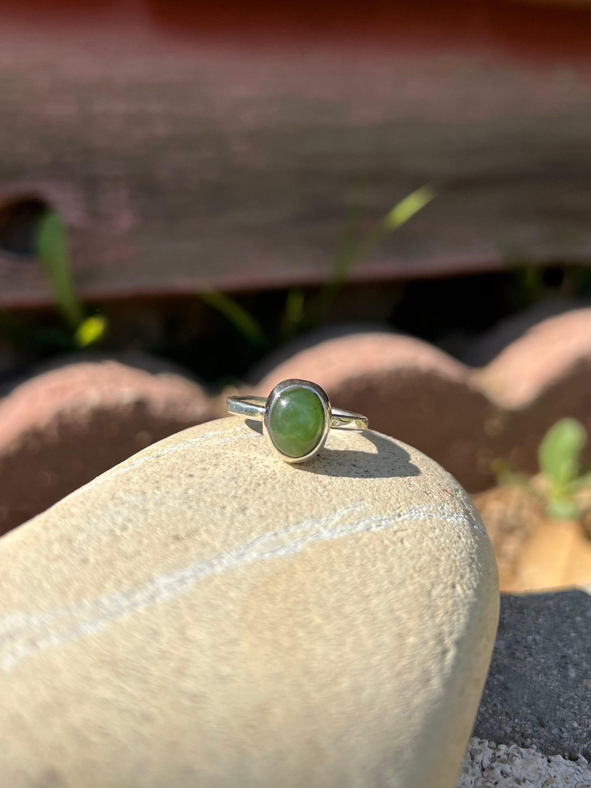 Ring with a green stone on a rock with a rustic background
