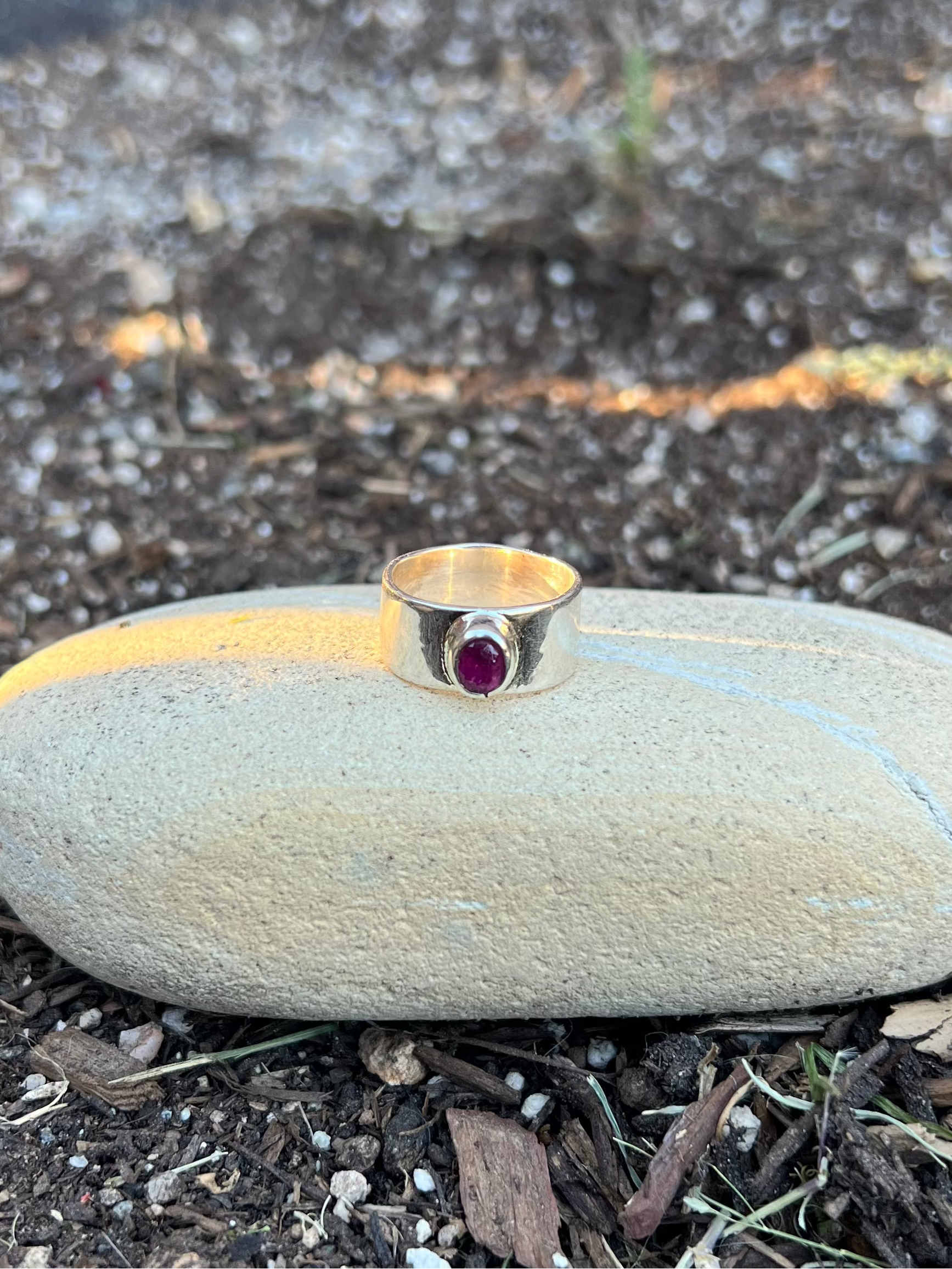 silver Ring with a tourmaline on a stone in soil