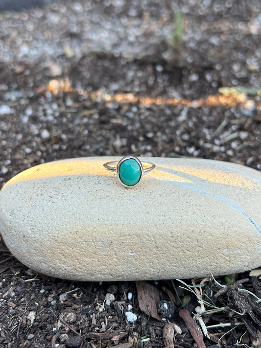 Ring with a turquoise stone on a stone in a garden setting