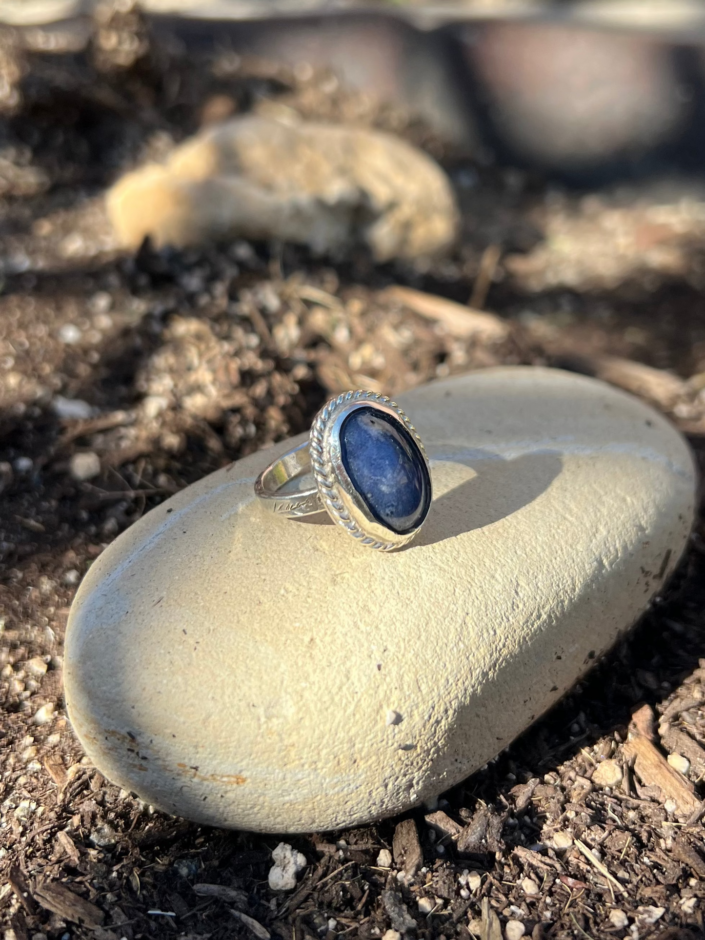Ring with a blue stone on a rock in an outdoor setting