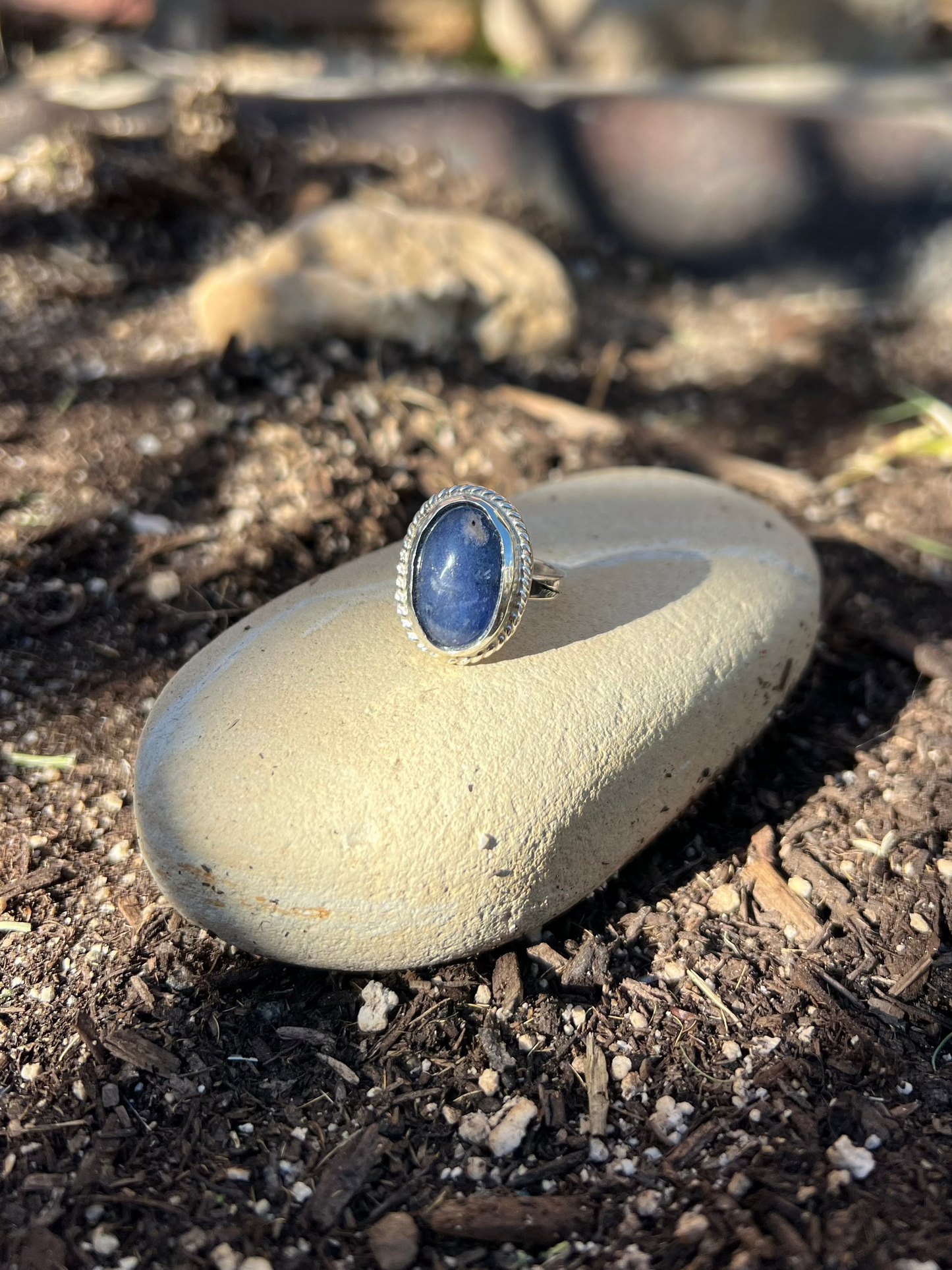 Ring with a blue stone on a rock outdoors
