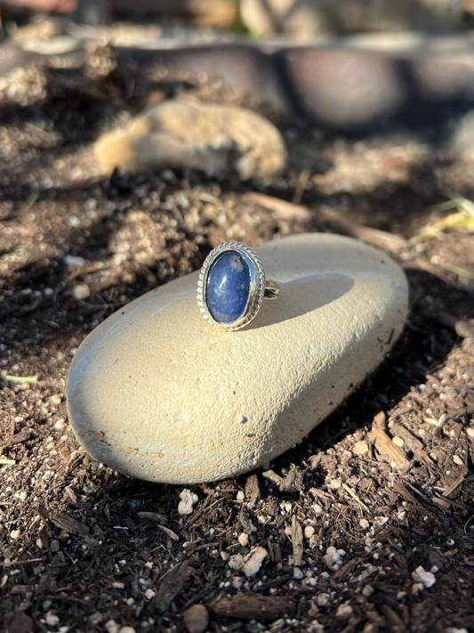 Ring with a blue stone on a rock outdoors