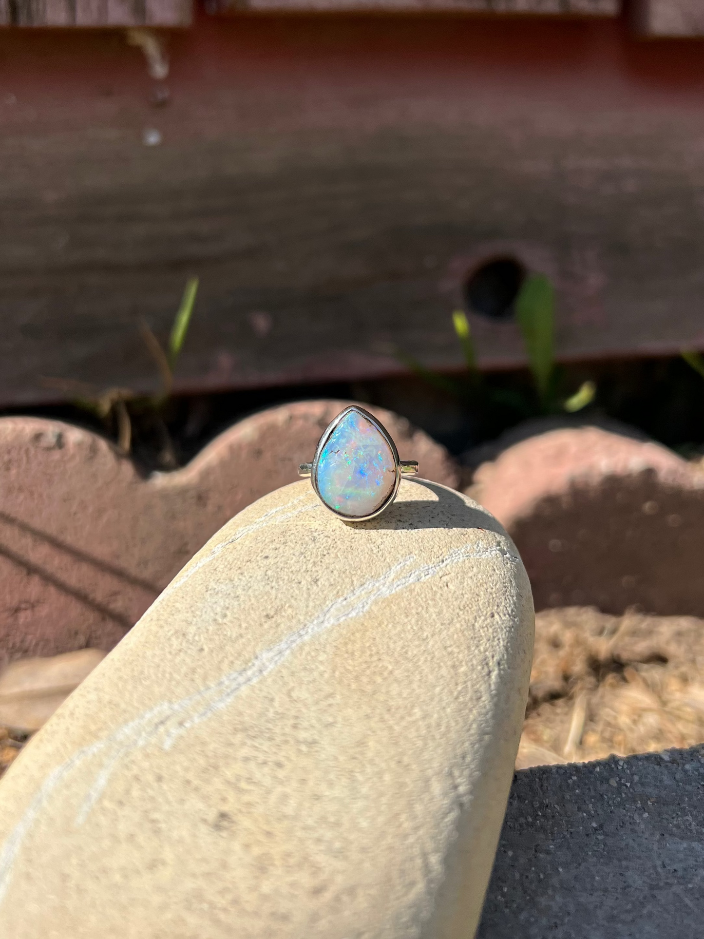 Ring with a opal on a stone surface with a wooden background
