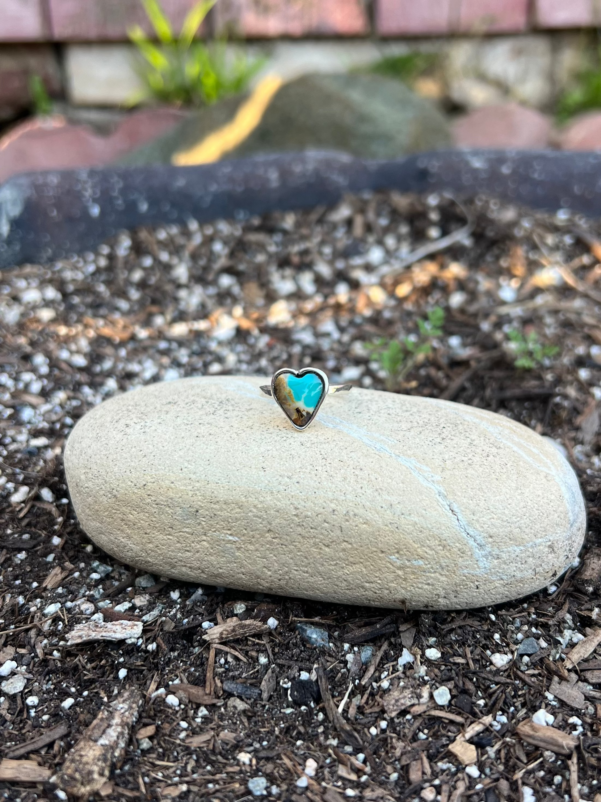 Ring with turquoise stone on a rock in a garden setting