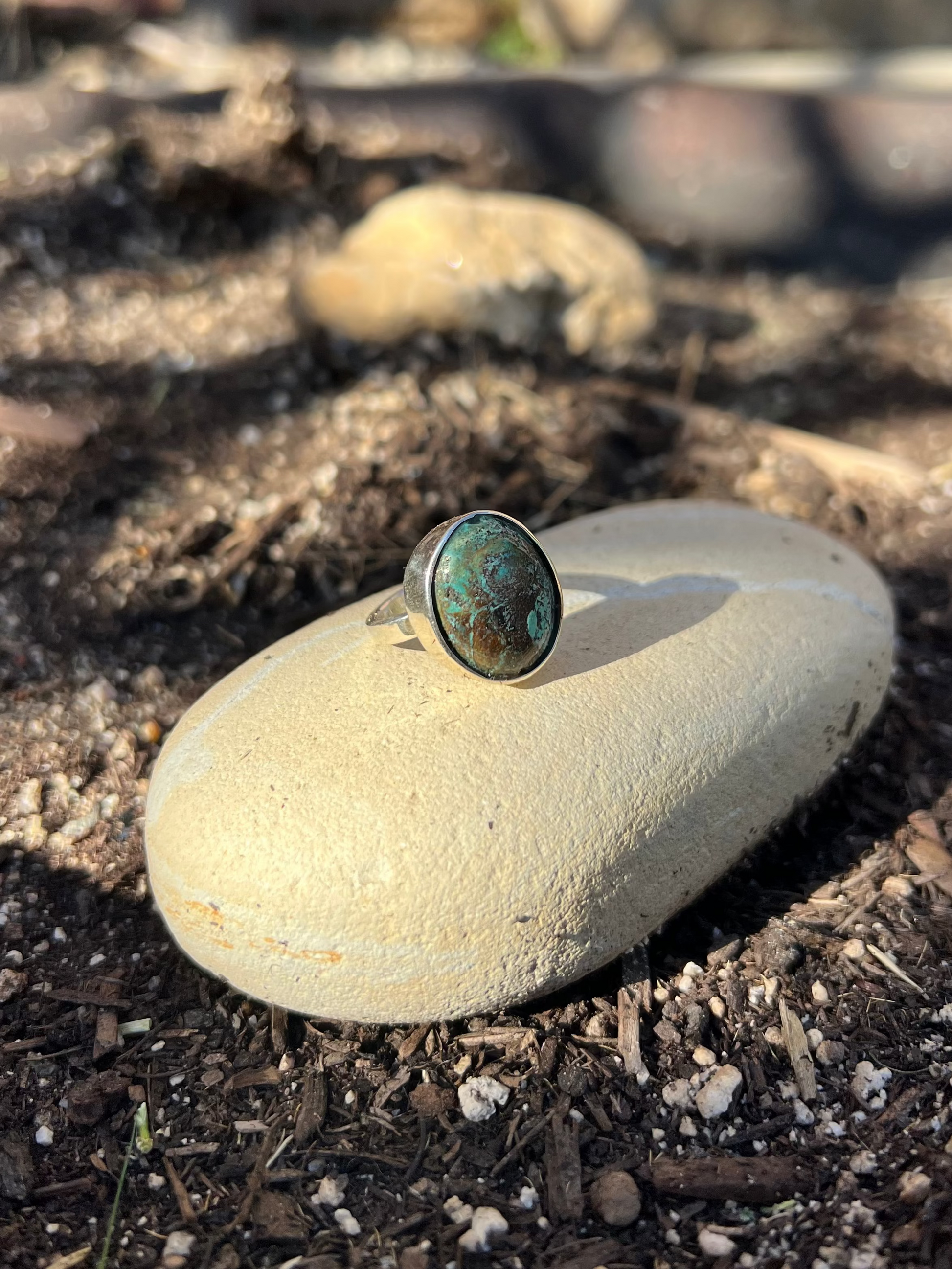 Ring with a green stone on a rock in an outdoor setting