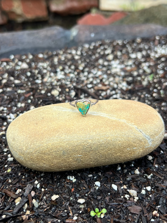 Ring with a green stone on a rock in a garden setting