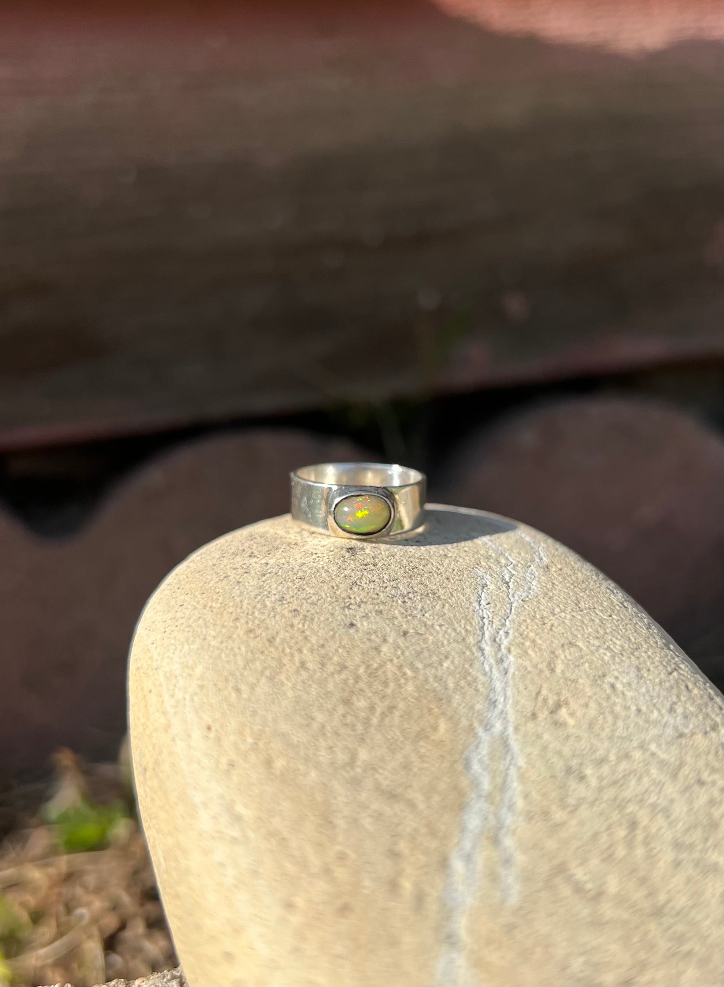 Silver ring with a green stone on a textured surface
